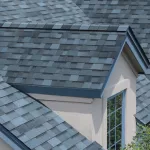 Blue asphalt shingles on a Maryland roof, illustrating roofing material lifespan.
